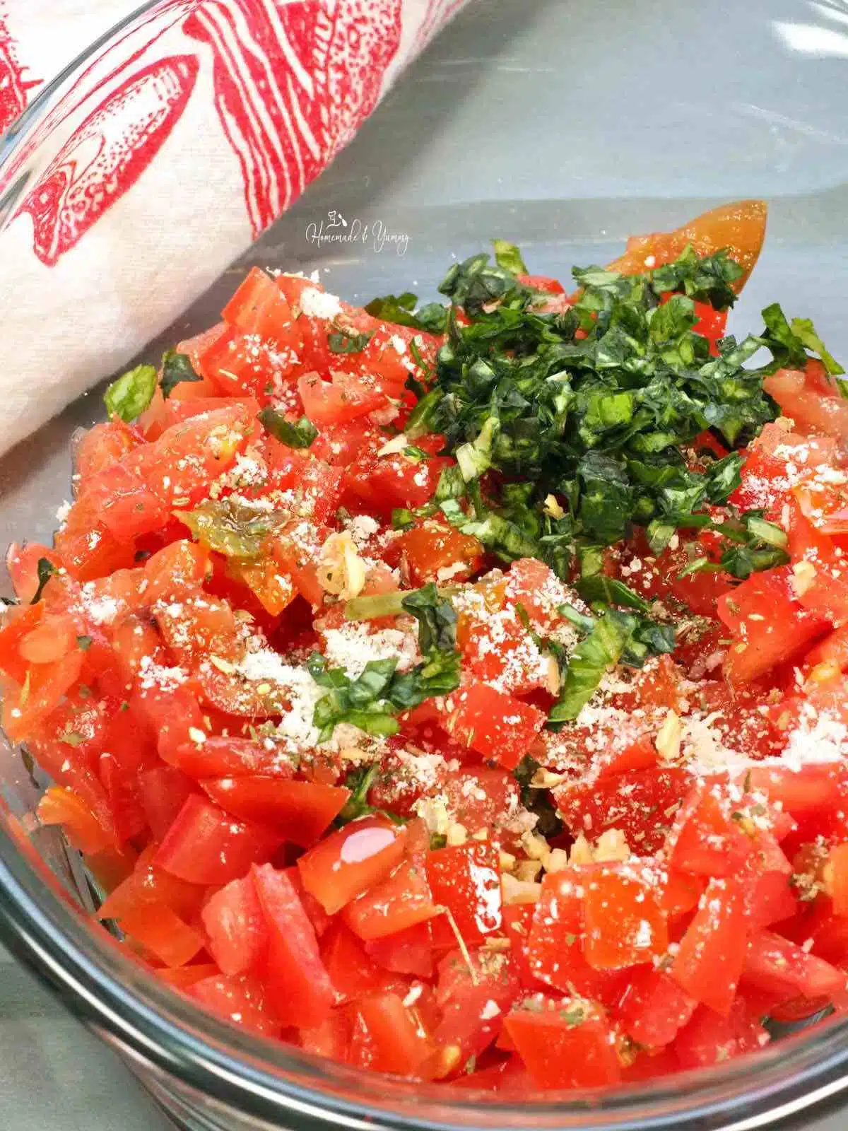 Bruschetta ingredients tossed in a bowl of diced tomatoes.