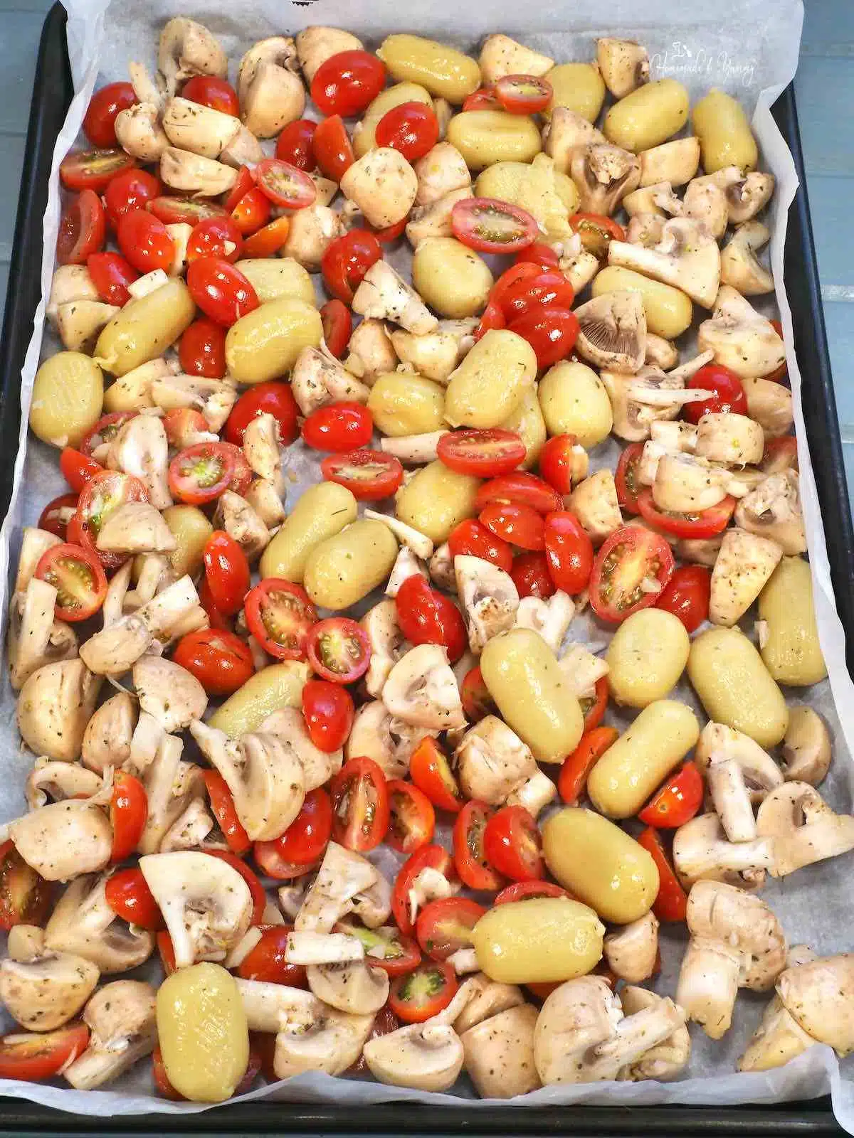 Gnocchi, mushrooms and tomatoes on a sheet pan ready for the oven.