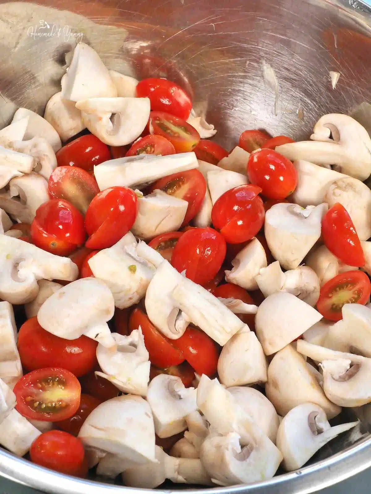 Cut up mushrooms and tomatoes in a bowl.