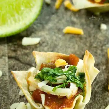 Guacamole appetizers in wonton cups with salsa and cheese.
