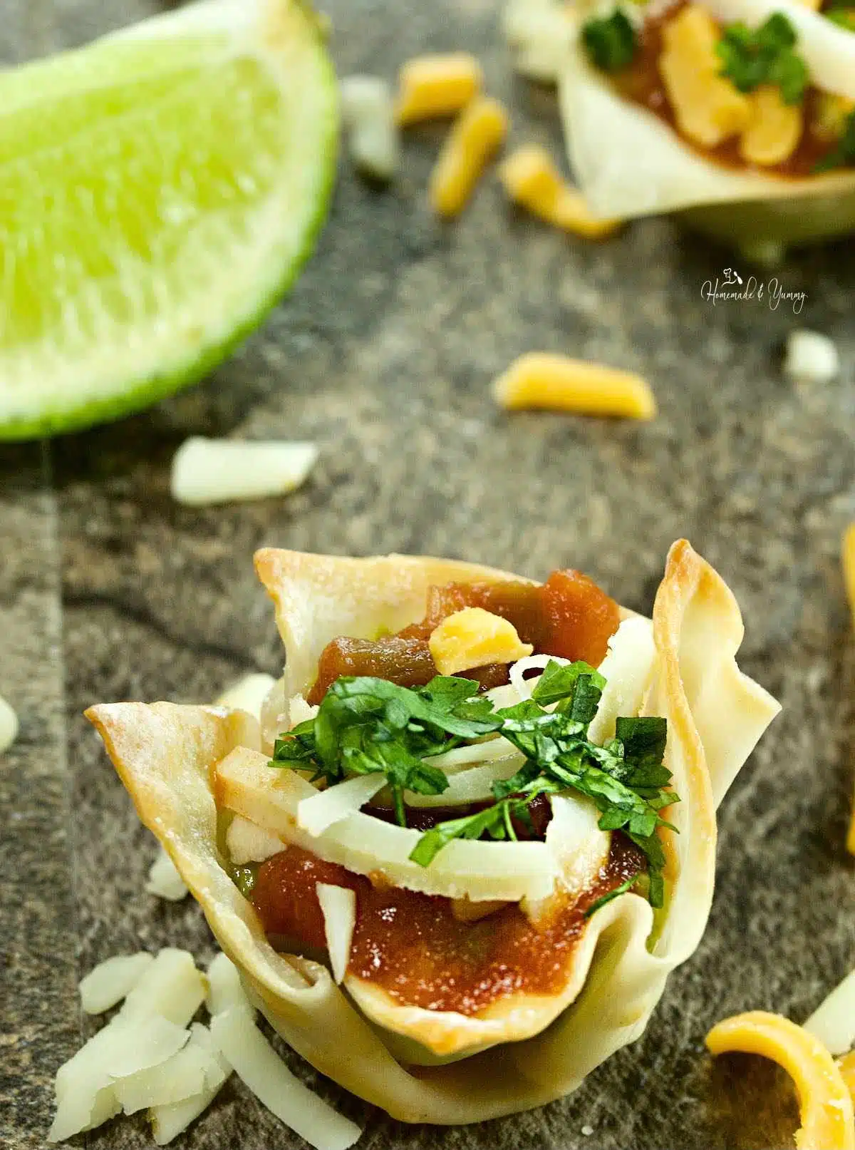 Guacamole appetizers in wonton cups with salsa and cheese.