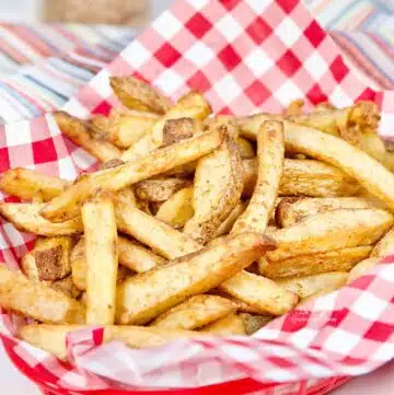 Spicy fries made in the air fryer piled in a red basket.