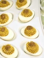 Green guacamole deviled eggs on a platter.