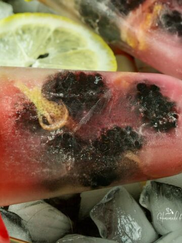 Blackberry and lemon ice pops on a tray of ice.