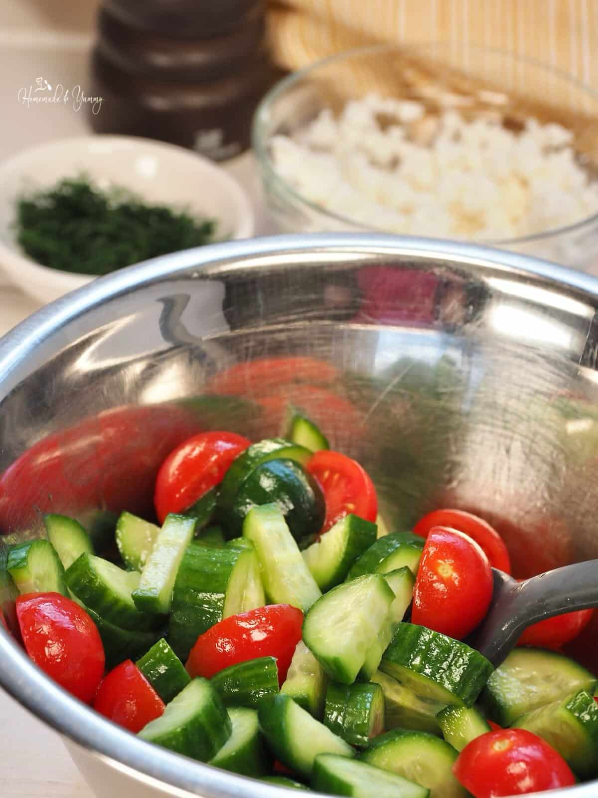 Mixing the salad dressing on the cucumbers and tomatoes.