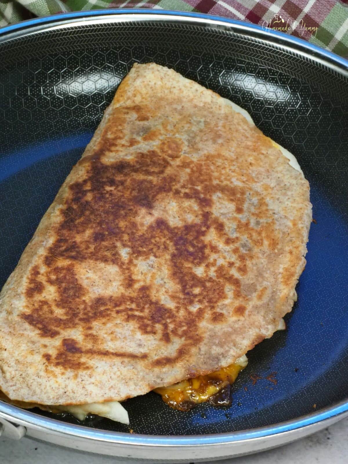 Grilling a quesadilla in a frying pan.
